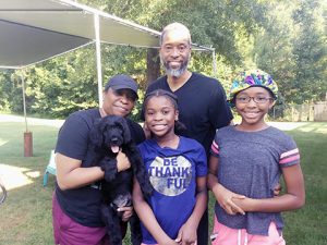 family of four with a black schnoodle puppy